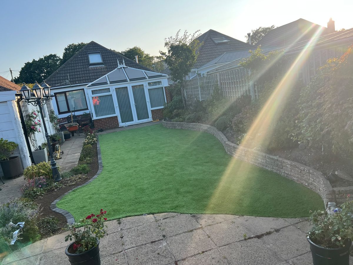 Artificial lawn with a curved block edge in a bungalow garden